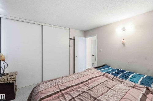 Room featuring white sliding closet doors, light-colored walls, and a textured ceiling - 203 11421 34 Street Nw, Edmonton, AB 