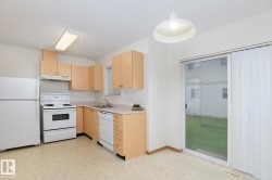 Kitchen featuring light wood-finish cabinetry and white appliances, including a range, dishwasher, and refrigerator - 