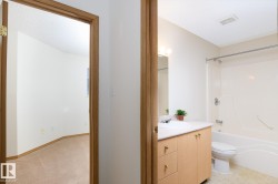 Bathroom featuring a light wood-finish vanity with an integrated sink, a large mirror, and a full bathtub with shower - 