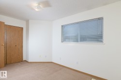 Room featuring neutral-toned carpet, white painted walls, and wood-finish bifold closet doors - 
