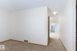 Carpeted interior space with a dropped ceiling and warm-toned baseboards - 