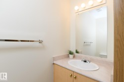 Bathroom vanity with light wood-finish cabinetry, an integrated white sink, and a light-colored countertop - 