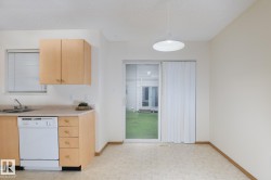 Compact kitchen area featuring wood-finish cabinetry, a white dishwasher, and a double-basin stainless steel sink - 