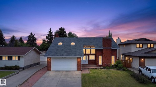 Two-story residence featuring a brick facade with a prominent chimney, large windows, and a two-car garage - 14808 55 Street, Edmonton, AB 