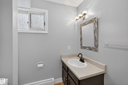 Bathroom featuring a vanity with a light-toned countertop, an undermount sink, and a dark-finish faucet - 