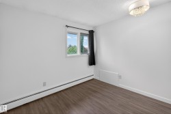 Room featuring wood-finish flooring, white baseboards, a window with exterior views, and a modern ceiling light fixture - 