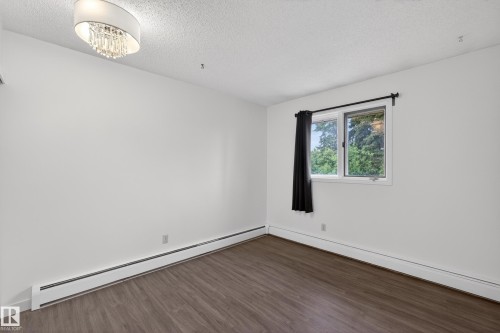 Bright room featuring a contemporary drum shade chandelier with crystal accents, wood-finish flooring, and white baseboards - 14808 55 Street, Edmonton, AB 