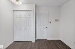 White bi-fold doors with round silver pulls, wood-finish flooring, white baseboards, and a contemporary ceiling light fixture - 