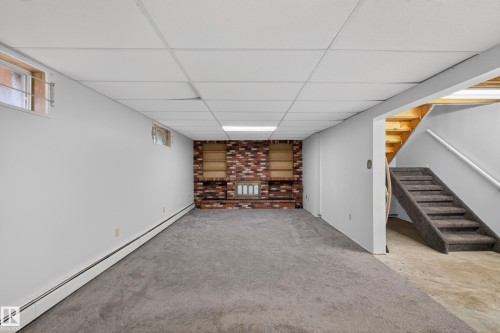 Finished room featuring a brick accent wall with built-in shelving, recessed lighting, and a drop ceiling - 14808 55 Street, Edmonton, AB 