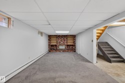 Finished room featuring a brick accent wall with built-in shelving, recessed lighting, and a drop ceiling - 
