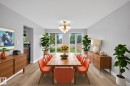 Bright dining area featuring a wood-finish dining table, contemporary chandelier, and large windows overlooking the backyard - 14808 55 Street, Edmonton, AB 