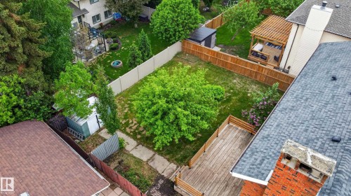 Expansive backyard featuring a large central lawn, a wooden deck, and mature trees - 14808 55 Street, Edmonton, AB 