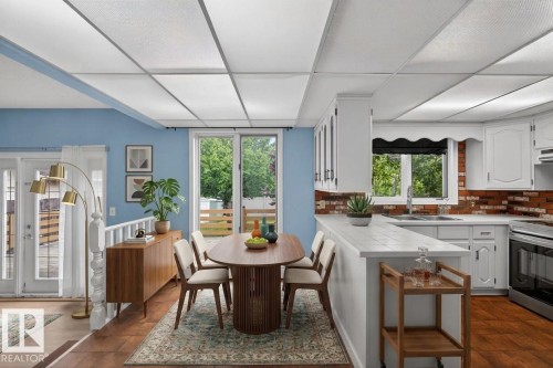 Dining area featuring wood-finish flooring, light blue wall paint, and double glass doors - 14808 55 Street, Edmonton, AB 