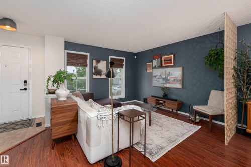 Living area featuring laminate flooring, dark accent wall, and multiple windows with woven blinds - 5964 South Terwillegar Boulevard, Edmonton, AB 