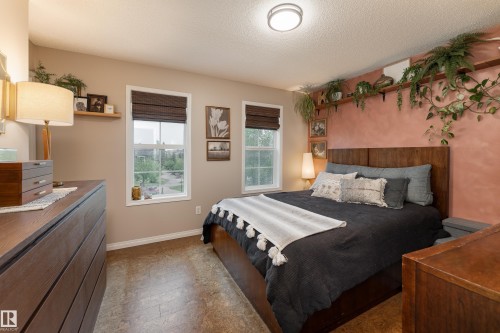 Spacious primary bedroom featuring two large windows, walk-in closet and cork flooring - 5964 South Terwillegar Boulevard, Edmonton, AB 