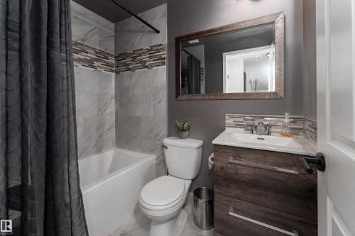3rd upgraded bathroom in basement featuring a white tub, marble-look wall tiles, and a mosaic tile accent band - 5964 South Terwillegar Boulevard, Edmonton, AB 