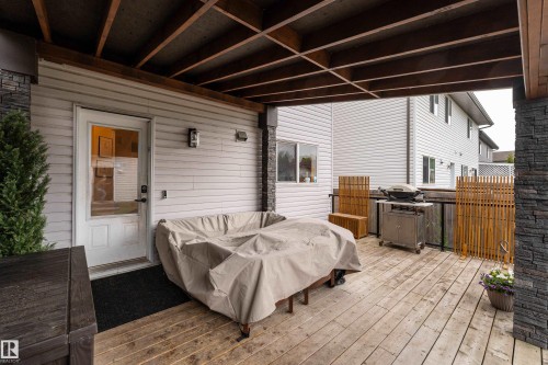 Expansive deck, partially covered plus open to sun, with stone-clad pillars, and a glass-paneled railing - 5964 South Terwillegar Boulevard, Edmonton, AB 
