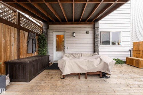 Wood-finish deck with an overhead structure, featuring a privacy fence with lattice detail, a white exterior door, and a horizontal sliding window - 5964 South Terwillegar Boulevard, Edmonton, AB 