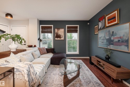 Living area featuring dark accent wall, wood-finish flooring, and two large windows with woven shades - 5964 South Terwillegar Boulevard, Edmonton, AB 