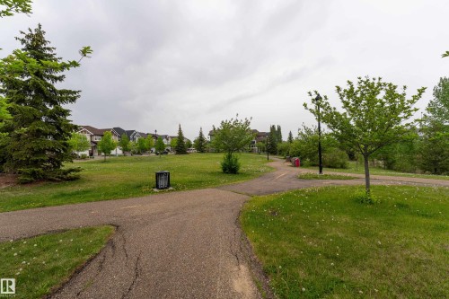This park is across the street! Paved walking paths traversing a green space with mature trees, bordered by residential properties - 5964 South Terwillegar Boulevard, Edmonton, AB 