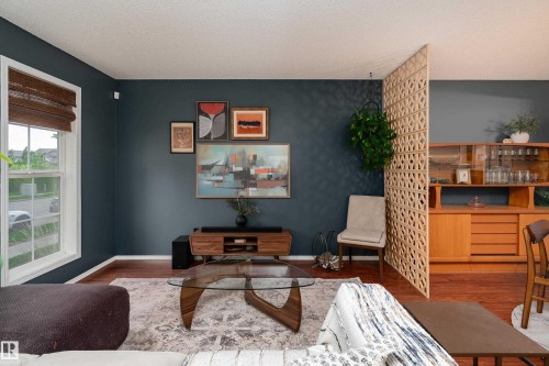 Hardwood-finish flooring extends throughout this living space, complemented by deep-toned walls and crisp white trim - 5964 South Terwillegar Boulevard, Edmonton, AB 