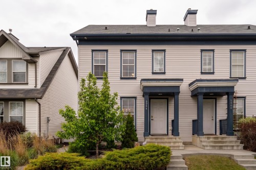 Duplex exterior featuring light-colored siding with dark trim accents and a dark shingle roof - 5964 South Terwillegar Boulevard, Edmonton, AB 