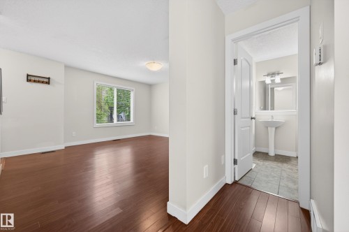 Bright living area featuring rich wood-finish flooring, a large window, and white trim - 48 8716 179 Avenue, Edmonton, AB 