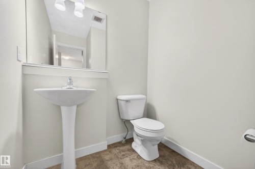 Pedestal sink with chrome faucet, wall-mounted mirror, and tile-finish flooring - 48 8716 179 Avenue, Edmonton, AB 