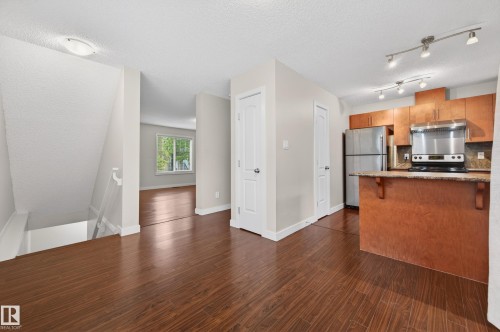 Kitchen with wood cabinetry, stainless steel appliances, and a breakfast bar - 48 8716 179 Avenue, Edmonton, AB 