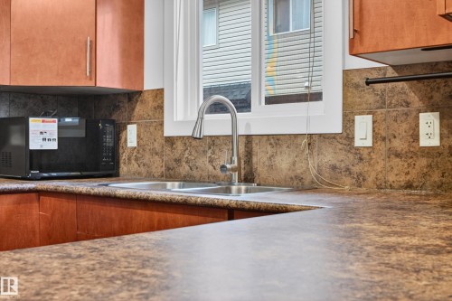 Kitchen featuring double stainless steel sink, gooseneck faucet, and white framed window - 48 8716 179 Avenue, Edmonton, AB 