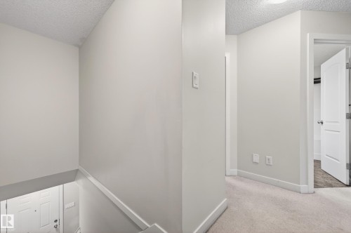 Upper-level hallway featuring neutral wall paint, white trim, and light-colored carpet flooring - 48 8716 179 Avenue, Edmonton, AB 