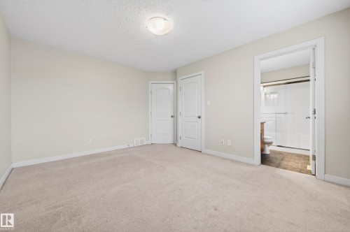 Spacious room featuring neutral carpeting, light-toned walls, and a ceiling-mounted light fixture - 48 8716 179 Avenue, Edmonton, AB 