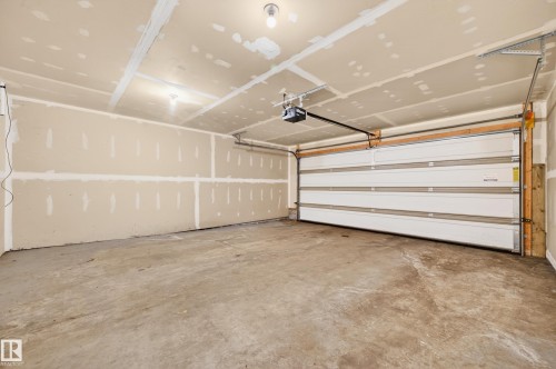 Spacious garage featuring a concrete floor, an overhead garage door, and an automatic garage door opener - 48 8716 179 Avenue, Edmonton, AB 