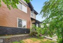 Contemporary exterior featuring horizontal siding in a warm tone, dark stacked stone detailing, and white-framed windows - 48 8716 179 Avenue, Edmonton, AB 