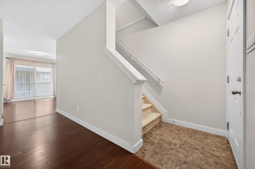 Entryway featuring wood-finish flooring, a carpeted staircase, and an exterior door - 48 8716 179 Avenue, Edmonton, AB 