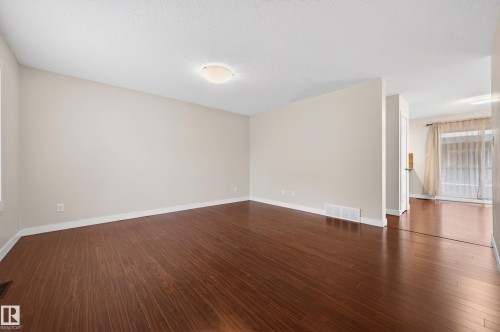 Spacious interior featuring rich wood-finish flooring, neutral wall tones, and white trim - 48 8716 179 Avenue, Edmonton, AB 