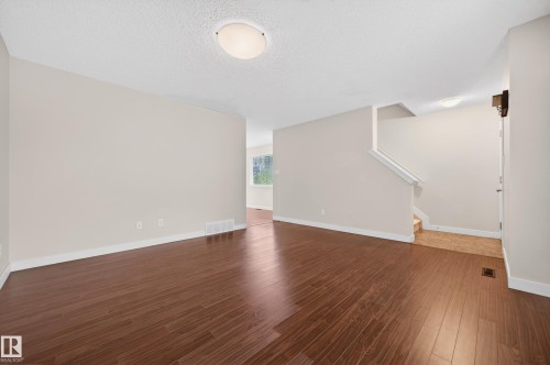Spacious interior featuring rich wood-finish flooring, light neutral wall tones, and white trim - 48 8716 179 Avenue, Edmonton, AB 