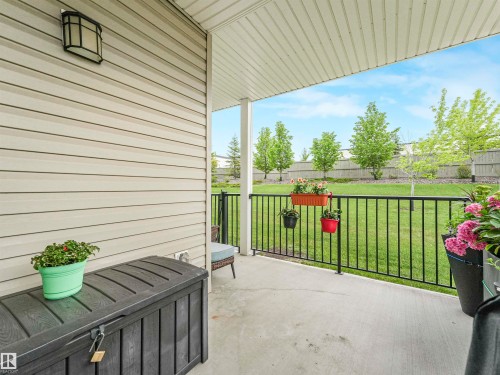 Covered concrete patio with white vinyl siding exterior and black metal railing - 1103 2 Augustine Crescent, Sherwood Park, AB 