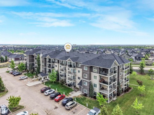 Multi-story residential building featuring balconies, dark shingle roofing, stone accents, and a dedicated parking area - 1103 2 Augustine Crescent, Sherwood Park, AB 