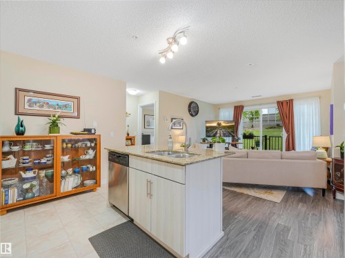 Kitchen island featuring a double-basin sink, stainless steel dishwasher, and light-toned cabinetry - 1103 2 Augustine Crescent, Sherwood Park, AB 