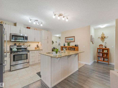 Kitchen featuring stainless steel appliances, light wood-finish cabinetry, a large center island with a granite countertop, and light tile flooring - 1103 2 Augustine Crescent, Sherwood Park, AB 