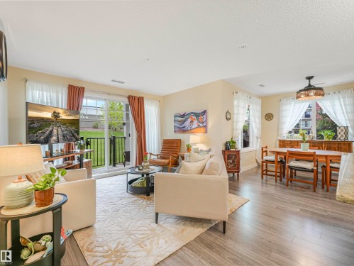 Open concept living space featuring wood-finish flooring, a glass sliding door leading to a balcony, and abundant natural light - 1103 2 Augustine Crescent, Sherwood Park, AB 
