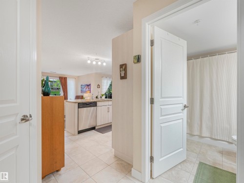 Open-concept living space featuring light-toned tile flooring, recessed lighting, and a kitchen with light-colored cabinetry and stainless steel appliances - 1103 2 Augustine Crescent, Sherwood Park, AB 