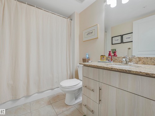 Bathroom with light-toned tiled flooring, a light wood-finish vanity with a built-in sink, a speckled stone countertop, and a white toilet - 1103 2 Augustine Crescent, Sherwood Park, AB 