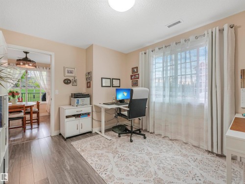 Versatile room featuring wood-finish flooring, a large window with privacy sheers, and neutral wall tones - 1103 2 Augustine Crescent, Sherwood Park, AB 
