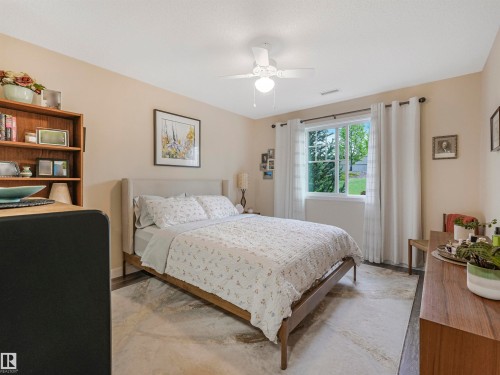 Bedroom featuring a window with white trim, a ceiling fan with light fixture, light-toned walls, and dark wood-finish flooring - 1103 2 Augustine Crescent, Sherwood Park, AB 