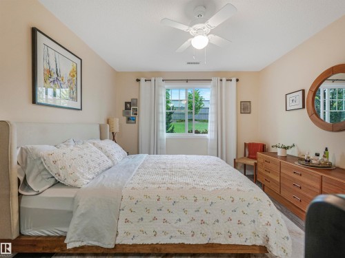 Bedroom featuring a window with exterior views, a ceiling fan with integrated lighting, and wood-finish flooring - 1103 2 Augustine Crescent, Sherwood Park, AB 