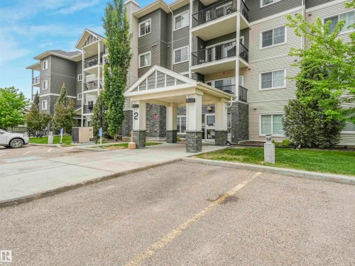 Multi-story building featuring a covered entrance with stone columns, multiple balconies with black railings, and a combination of horizontal siding and stone exterior finishes - 1103 2 Augustine Crescent, Sherwood Park, AB 
