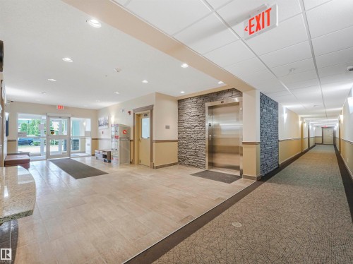 Lobby area featuring tile flooring, stainless steel elevator with stone-finish accent wall, contemporary lighting, and direct exterior access - 1103 2 Augustine Crescent, Sherwood Park, AB 