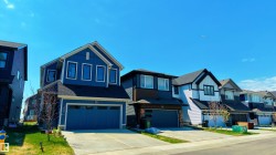 Contemporary two-story residence featuring blue siding, white trim, a dark shingle roof, and an attached two-car garage - 